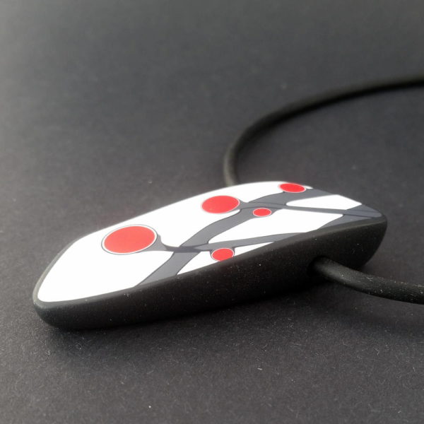 Handmade necklace with a single bead showing a graphic flower bud motif in red, on a white background with a charcoal border. It is approximately 2.6 cm wide and 6.4 cm long and hangs on a black adjustable cord.