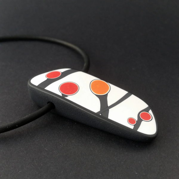 Handmade pendant showing a graphic flower bud motif in orange tones, on a white background with a charcoal border. It is approximately 2.6 cm wide and 6.4 cm long and hangs on a black adjustable cord.