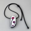 Handmade shield shaped necklace featuring an abstract flower bud motif in plum on a white background, with charcoal border. It is approximately 2.6 cm wide and 6. long and hangs on a black adjustable cord.