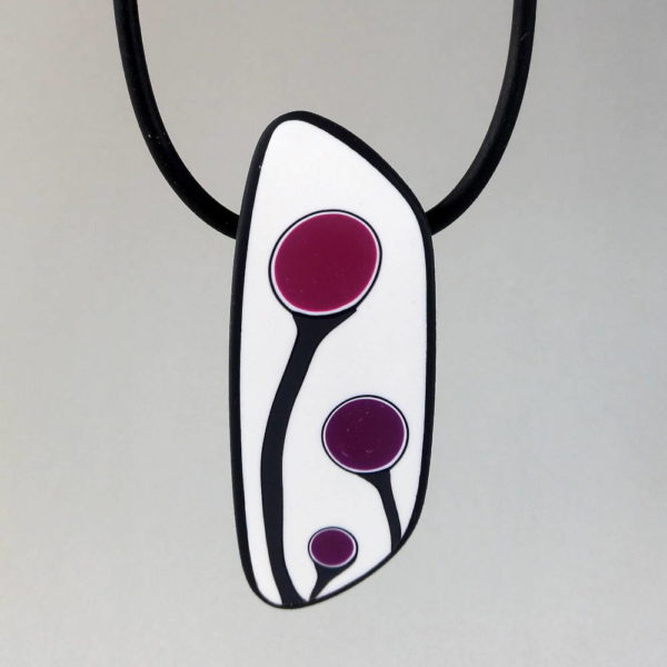 Handmade shield shaped necklace featuring an abstract flower bud motif in plum on a white background, with charcoal border. It is approximately 2.6 cm wide and 6. long and hangs on a black adjustable cord.