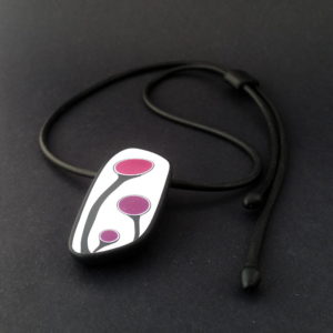 Handmade shield shaped necklace featuring an abstract flower bud motif in plum on a white background, with charcoal border. It is approximately 2.6 cm wide and 6. long and hangs on a black adjustable cord.