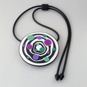 Large handmade pendant with organically shaped concentric black & white circles, and irregular dots of purple, green and magenta. It's approximately 6.6cm in diameter and hangs on a black adjustable cord.