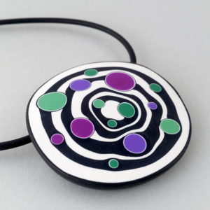 Large handmade pendant with organically shaped concentric black & white circles, and irregular dots of purple, green and magenta. It's approximately 6.6cm in diameter and hangs on a black adjustable cord.