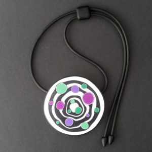 Large handmade pendant with organically shaped concentric black & white circles, and irregular dots of purple, green and magenta. It's approximately 6.6cm in diameter and hangs on a black adjustable cord.