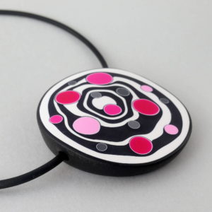 Large handmade pendant with organically-shaped concentric black and white circles, and irregular dots in various pinks. It is approximately 6.6cm in diameter and hangs on a black adjustable cord.