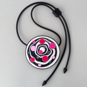 Large handmade pendant with organically-shaped concentric black and white circles, and irregular dots in various pinks. It is approximately 6.6cm in diameter and hangs on a black adjustable cord.