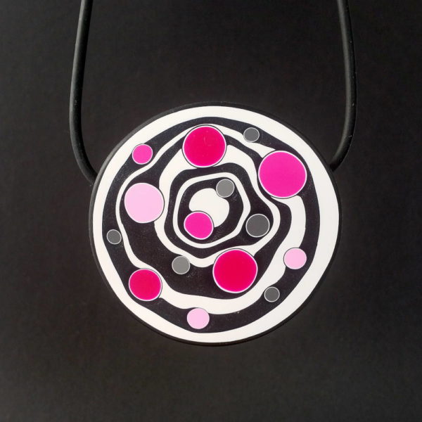 Large handmade pendant with organically-shaped concentric black and white circles, and irregular dots in various pinks. It is approximately 6.6cm in diameter and hangs on a black adjustable cord.