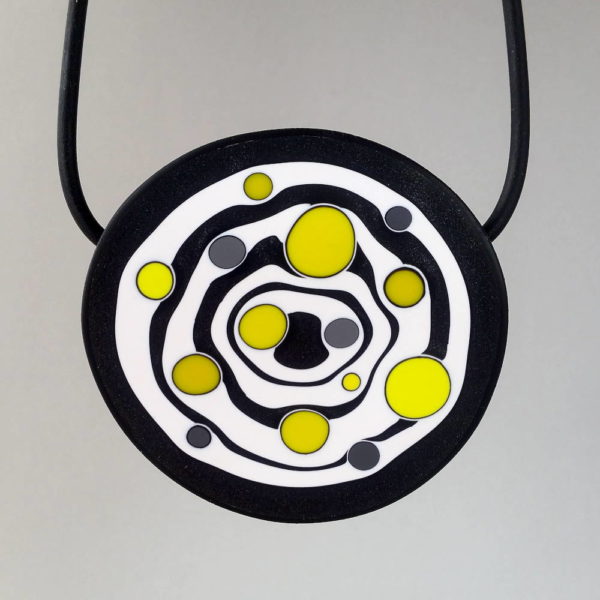 Large handmade pendant with organically-shaped concentric black and white circles, and irregular dots of bright yellow. It is approximately 6.6cm in diameter and hangs on a black adjustable cord.