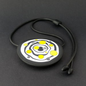 Large handmade pendant with organically-shaped concentric black and white circles, and irregular dots of bright yellow. It is approximately 6.6cm in diameter and hangs on a black adjustable cord.