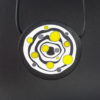 Large handmade pendant with organically-shaped concentric black and white circles, and irregular dots of bright yellow. It is approximately 6.6cm in diameter and hangs on a black adjustable cord.