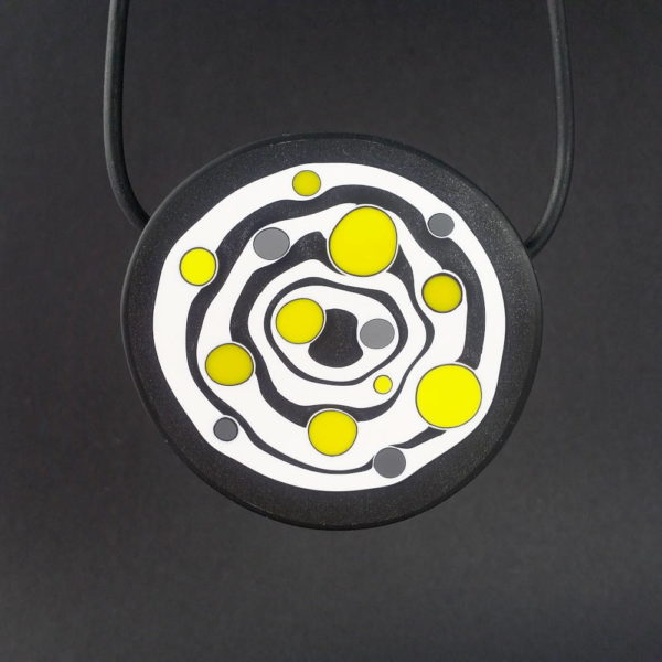 Large handmade pendant with organically-shaped concentric black and white circles, and irregular dots of bright yellow. It is approximately 6.6cm in diameter and hangs on a black adjustable cord.