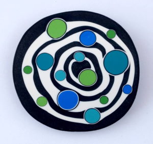 Handmade large bead with concentric black and white circles, and bright blue and green irregular dots.