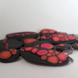 Handmade long necklace with individually crafted flat beads in vibrant orange and magenta on a black, textured background. Length approx. 120cm.