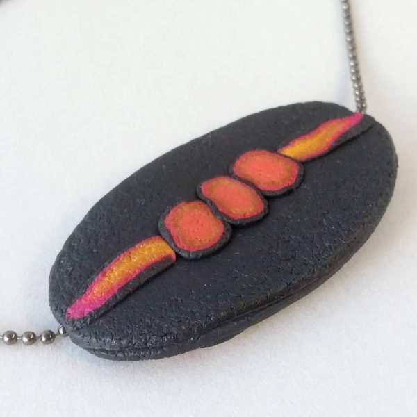 Handmade long necklace with individually crafted flat beads in vibrant orange and magenta on a black, textured background. Length approx. 120cm.