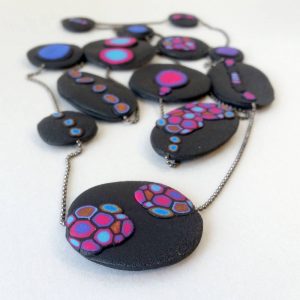 Handmade long necklace (120cm) with individually crafted organically shaped beads in a vivid combination of purple and magenta dots.