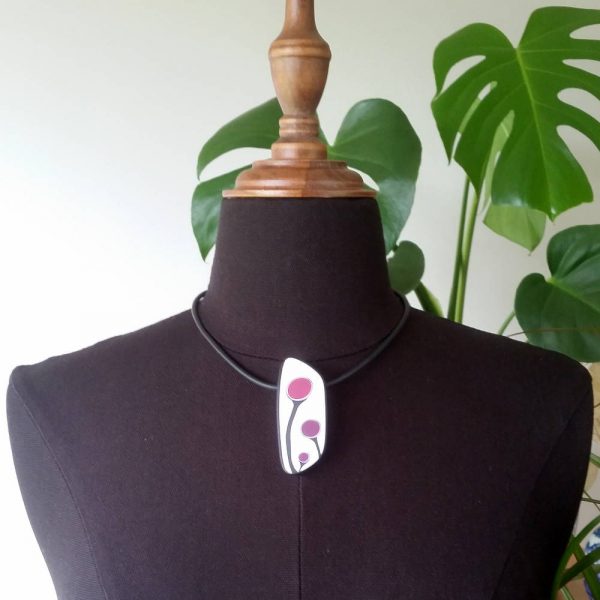 Handmade shield shaped necklace featuring an abstract flower bud motif in plum on a white background, with charcoal border. It is approximately 2.6 cm wide and 6.4cm long and hangs on a black adjustable cord.