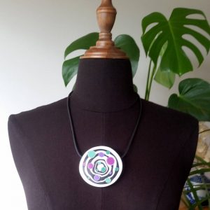 Large handmade pendant with organically shaped concentric black & white circles, and irregular dots of purple, green and magenta. It's approximately 6.6cm in diameter and hangs on a black adjustable cord.