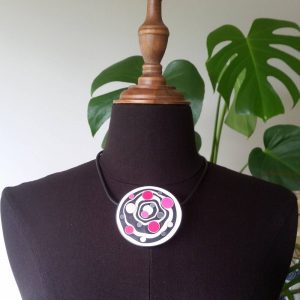 Large handmade pendant with organically-shaped concentric black and white circles, and irregular dots in various pinks. It is approximately 6.6cm in diameter and hangs on a black adjustable cord.