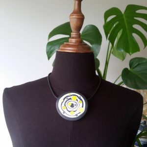 Large handmade pendant with organically-shaped concentric black and white circles, and irregular dots of bright yellow. It is approximately 6.6cm in diameter and hangs on a black adjustable cord.