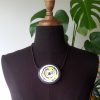 Large handmade pendant with organically-shaped concentric black and white circles, and irregular dots of bright yellow. It is approximately 6.6cm in diameter and hangs on a black adjustable cord.