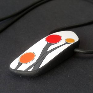 Handmade pendant showing a graphic flower bud motif in red and orange tones, on a white background with a charcoal border. It is approximately 2.6 cm wide and 6.4 cm long and hangs on a black adjustable cord.