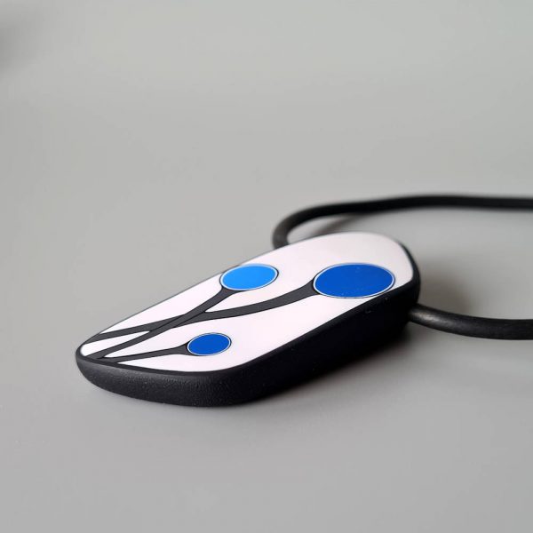 Handmade shield shaped necklace featuring an abstract flower bud motif in blue on a white background, with charcoal border. It is approximately 2.6 cm wide and 6.4cm long and hangs on a black adjustable cord.